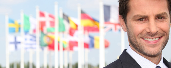 Man in business attire in front of international flags