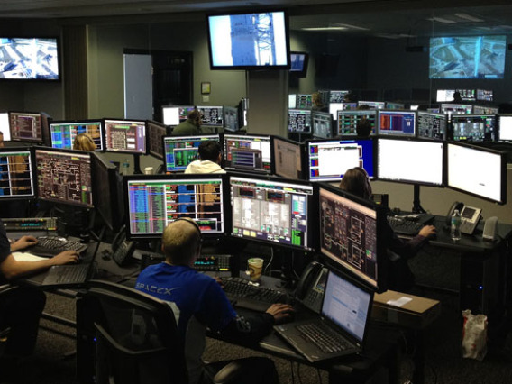 Photo of people working in control room with multiple computer screens